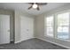 A small, unfurnished bedroom features neutral paint, carpet, a ceiling fan, two windows, and a closet at 1443 Smokey Mountain Dr, Zebulon, NC 27597
