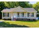 Charming home features a quaint front porch, green shutters, a well-manicured lawn, and an inviting entryway at 1443 Smokey Mountain Dr, Zebulon, NC 27597