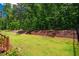 Backyard features a fenced-in lawn backed by a wooded area with a wood retaining wall at 151 Monteith Dr, Chapel Hill, NC 27516