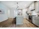 Bright kitchen features stainless appliances, white cabinets, an island with barstool seating, and wood floor at 151 Monteith Dr, Chapel Hill, NC 27516