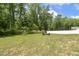 Spacious backyard with lush lawn, mature trees, and fire pit area for outdoor gatherings at 159 Mitchell Manor Dr, Angier, NC 27501
