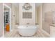 Spa-like bathroom featuring a modern soaking tub, walk-in shower, and custom tile work with a view into a walk-in closet at 1952 Combine Cir, Apex, NC 27502