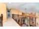 View of the upstairs hallway with decorative iron railing, overlooking the living room with stone fireplace feature at 1952 Combine Cir, Apex, NC 27502