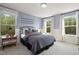 Cozy bedroom featuring a large bed, bedside table, and natural light from two large windows with views of the treeline at 199 Sugar Pine Drive, Franklinton, NC 27525