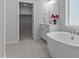 Bright bathroom featuring soaking tub, walk-in closet, and large window at 236 Artisan Park Dr, Wake Forest, NC 27587