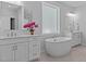 Bathroom with soaking tub, dual vanities, white cabinetry, and elegant modern fixtures at 236 Artisan Park Dr, Wake Forest, NC 27587