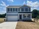 Two-story home featuring a two-car garage, a black front door, and double-hung windows under a blue sky at 24 Grove Township Way, Angier, NC 27501