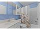 Bright blue bathroom with white vanity, toilet, and shower with floral curtain at 25 Ballinger Dr, Youngsville, NC 27596