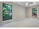 Carpeted bedroom with neutral walls, ceiling fan, and views to wooded outdoors from two windows at 2511 Bexley Ave, Durham, NC 27707