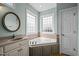 A bright bathroom boasts a soaking tub under windows and a round mirror above the sink at 281 Derwin Dr, Timberlake, NC 27583