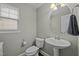 Cozy half bathroom with a pedestal sink, neutral walls, and a window for natural light at 302 Kinney Glenn Ct, Durham, NC 27713