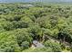 Wide aerial shot of a home nestled among dense green trees, with a road nearby at 3204 Manor Ridge Dr, Raleigh, NC 27603