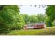 Rear view of the home with a sunroom and a deck, surrounded by lush greenery at 3204 Manor Ridge Dr, Raleigh, NC 27603