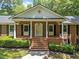 Close up of the front porch featuring brick steps, white columns and manicured bushes at 3204 Manor Ridge Dr, Raleigh, NC 27603