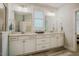 Bright bathroom featuring dual sinks, white cabinets, large mirrors and shuttered window at 328 Boone St, Chapel Hill, NC 27516