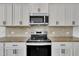 Bright kitchen featuring stainless steel appliances, stylish tile backsplash, and white cabinetry at 384 Grey Hawk Dr, Garner, NC 27529