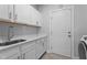 Laundry room featuring white cabinetry and a stainless-steel sink with modern fixtures at 412 Kavanaugh Rd, Wake Forest, NC 27587