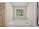 Bright bathroom featuring a soaking tub beneath a window and separate glass shower at 4608 Regency Dr, Durham, NC 27713