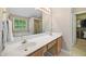 Bathroom featuring double sinks, a large mirror, and a view of the walk-in closet and bathtub at 4608 Regency Dr, Durham, NC 27713