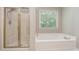 Bathroom featuring a shower with glass door, white tub, window with natural light, and gold accents at 4608 Regency Dr, Durham, NC 27713