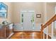 Bright foyer with hardwood floors, white door, sidelights and transom, wainscoting, and staircase at 4608 Regency Dr, Durham, NC 27713