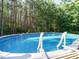 Above ground swimming pool with a clear blue water, surrounded by decking and ladders for easy access at 49 Mount Joy Pl, Sanford, NC 27330