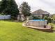Spacious backyard featuring an above-ground pool, playhouse, lush lawn, and privacy fencing at 506 Wildwood Ln, Graham, NC 27253