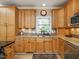 Bright kitchen featuring custom wood cabinets, granite countertops, modern appliances, and a farmhouse sink with a view at 506 Wildwood Ln, Graham, NC 27253