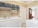 Well-lit laundry room with a large sink, white cabinets, and overhead shelving at 506 Wildwood Ln, Graham, NC 27253