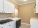 Functional laundry room featuring modern machines, white cabinets, sink, and tile floors at 506 Wildwood Ln, Graham, NC 27253