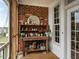 Cozy screened-in porch featuring a potting table, brick accent wall, and access to outdoor light at 506 Wildwood Ln, Graham, NC 27253