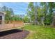 View of the wooden back deck with a lush green backyard and wooded perimeter at 509 Olive Branch Rd, Durham, NC 27703