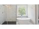 Bright bathroom featuring a freestanding tub, glass shower, and a large window for natural light at 509 Olive Branch Rd, Durham, NC 27703
