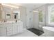 Modern bathroom showcasing a double vanity, glass shower, bathtub, and marble-style tile floors at 509 Olive Branch Rd, Durham, NC 27703