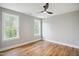 Bright bedroom featuring hardwood floors, neutral walls, a ceiling fan, and light-filled windows at 509 Olive Branch Rd, Durham, NC 27703