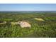 Expansive aerial view of a wooded property with multiple structures, cleared land and a distant view of a lake at 525 Turtle Creek Farm Rd, Apex, NC 27523