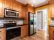 This traditional kitchen has wooden cabinetry, stainless appliances, and access to another room at 525 Turtle Creek Farm Rd, Apex, NC 27523