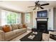 Cozy living room with fireplace, large windows, comfortable seating, and a ceiling fan at 525 Turtle Creek Farm Rd, Apex, NC 27523