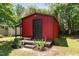 Exterior of a red shed with black door, complemented by landscaping and nestled among mature trees at 6225 Jones Farm Rd, Wake Forest, NC 27587