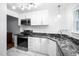 Modern kitchen features sleek white cabinetry, stainless steel appliances and black marble countertops at 6565 New Market Way, Raleigh, NC 27615