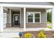 Close-up of a cozy front porch with brick accents, white columns, and a SimpliSafe security sign at 680 Winesap Dr, Graham, NC 27253