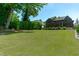 A vast green lawn and a glimpse of the home's backyard, framed by mature trees at 702 Wimbleton Dr, Raleigh, NC 27609