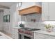 The kitchen features a marble backsplash, custom wood range hood, and stainless steel appliances at 702 Wimbleton Dr, Raleigh, NC 27609