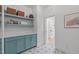 Bright laundry room with blue cabinets, open shelving, and stylish patterned tile flooring at 702 Wimbleton Dr, Raleigh, NC 27609