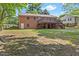 Brick home featuring a spacious backyard with a wooden deck and mature trees at 717 Fairfield St, Burlington, NC 27215