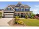 Beautiful two-story home with a stone and gray shingle exterior, lush landscaping, and a welcoming front porch at 7700 Stonehenge Farm Ln, Raleigh, NC 27613