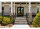 Elegant stone stairs lead to a covered front porch and stately, black double doors at 7700 Stonehenge Farm Ln, Raleigh, NC 27613