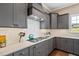 Contemporary kitchen featuring gray cabinets, white backsplash, and stainless steel appliances at 7700 Stonehenge Farm Ln, Raleigh, NC 27613