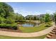 Beautiful pond view surrounded by lush landscaping and a paved walkway, ideal for leisurely strolls at 7700 Stonehenge Farm Ln, Raleigh, NC 27613