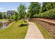 Scenic view of a paved walking path beside a pond, complemented by manicured landscaping at 7700 Stonehenge Farm Ln, Raleigh, NC 27613